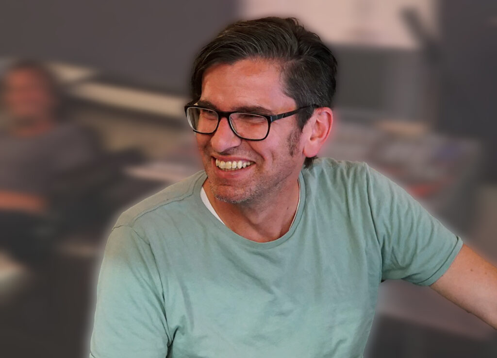 Ein sympathischer Mann mittlerem alters lacht und schaut nach links